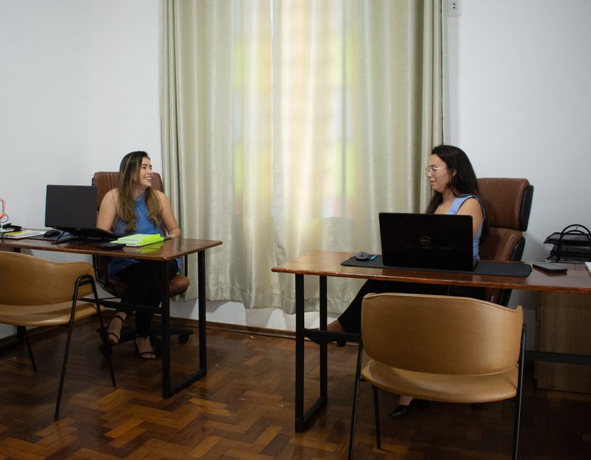 Um escritório de contabilidade com um funcionário trabalhando no computador enquanto outro atende ao telefone
